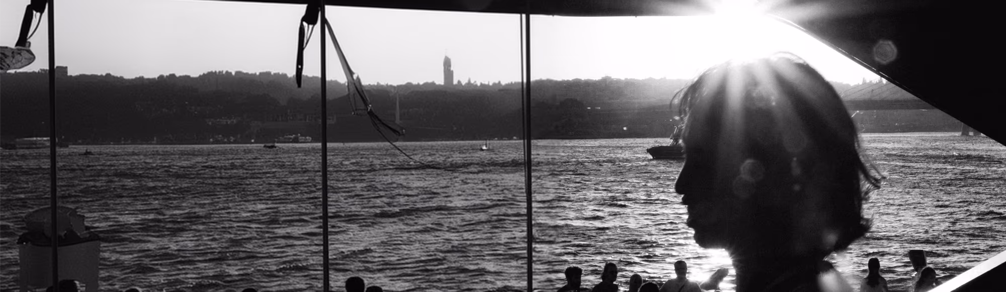 A crowd on the waterfront at sunset, a city skyline across the water